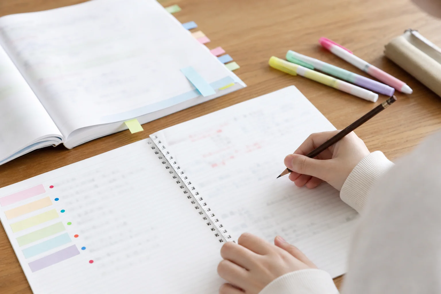 中2の学年末テストに向けて、単元名と印を書き込んだ苦手単元リストのノートと問題集が並ぶ机の手元の写真